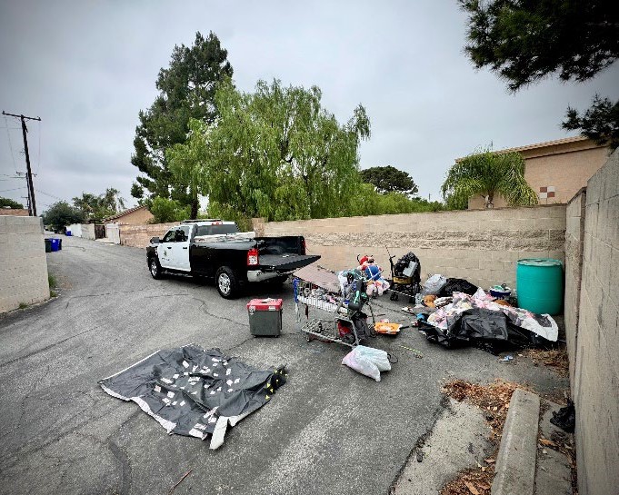 A before picture of a police truck ready to load abandoned items and trash in an alley
